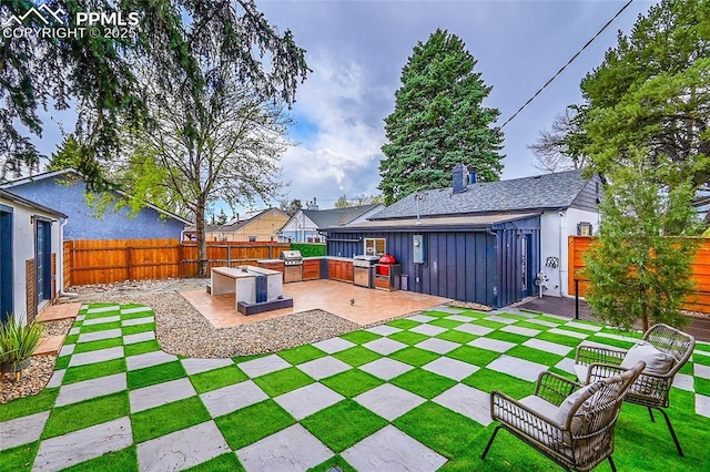 view of yard with a patio area, an outdoor kitchen, and a fenced backyard