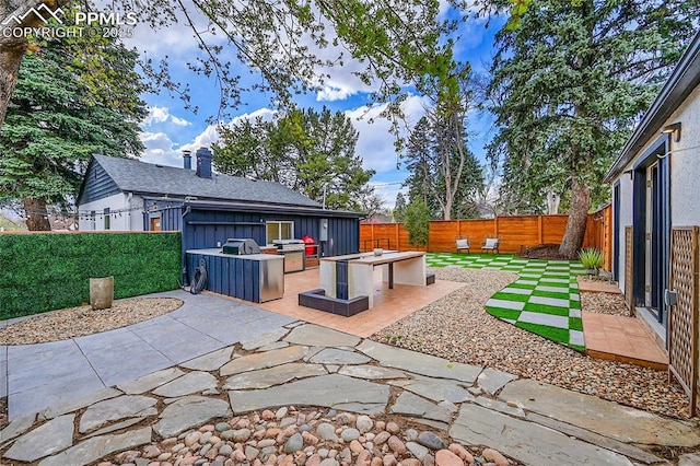 view of patio / terrace with a fenced backyard, an outdoor kitchen, and area for grilling