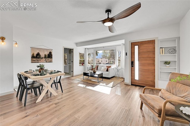 living room with a ceiling fan, baseboards, and light wood-style flooring