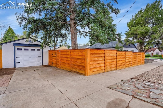 detached garage featuring driveway and fence