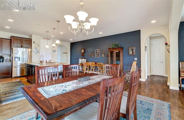 9825 Golf Crest Dr, Peyton, CO 80831 - dining area featuring baseboards, arched walkways, a notable chandelier, dark wood-style flooring, and recessed lighting