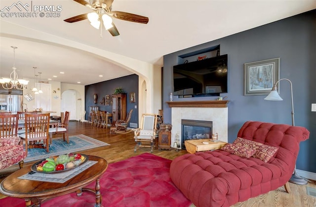 9825 Golf Crest Dr, Peyton, CO 80831 - living room with ceiling fan with notable chandelier, arched walkways, a glass covered fireplace, recessed lighting, and wood finished floors