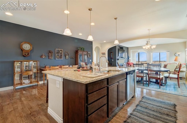 9825 Golf Crest Dr, Peyton, CO 80831 - kitchen featuring arched walkways, wood finished floors, stainless steel dishwasher, and dark brown cabinetry