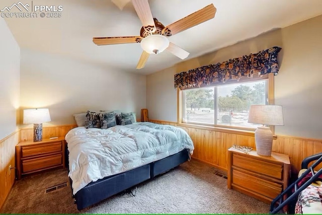 carpeted bedroom featuring wooden walls and wainscoting