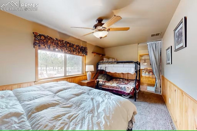 bedroom with visible vents, a wainscoted wall, a ceiling fan, and carpet