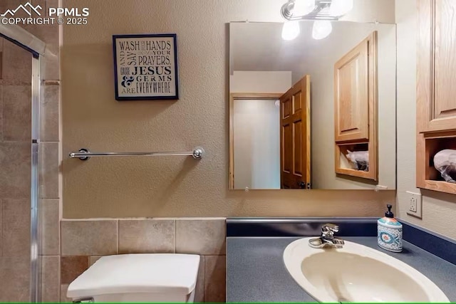 bathroom featuring a shower with door, a sink, and toilet