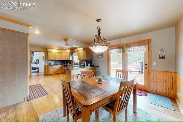 dining space with wood walls, light wood-style flooring, and wainscoting