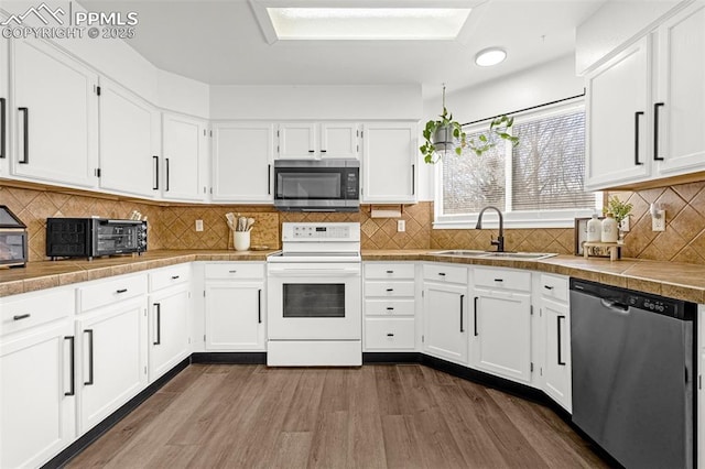 kitchen with a sink, appliances with stainless steel finishes, white cabinetry, and dark wood finished floors