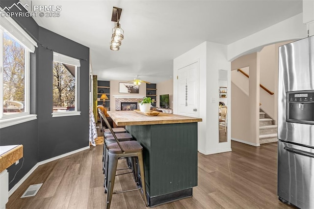 kitchen featuring butcher block counters, stainless steel refrigerator with ice dispenser, visible vents, and dark wood-style flooring