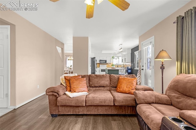living area featuring plenty of natural light, ceiling fan, baseboards, and dark wood finished floors