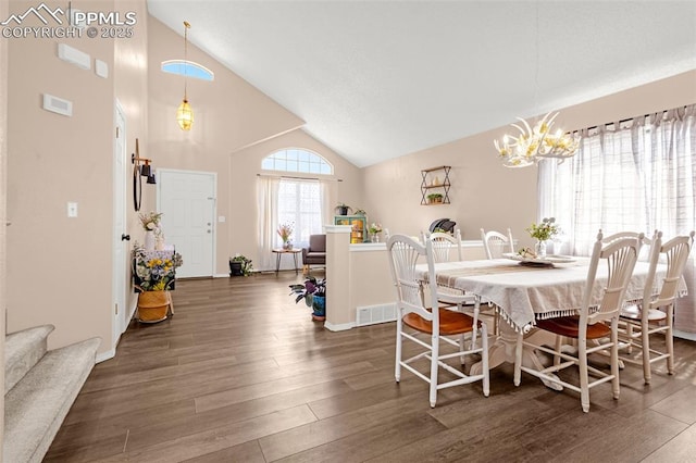 dining space featuring an inviting chandelier, high vaulted ceiling, visible vents, wood finished floors, and stairs