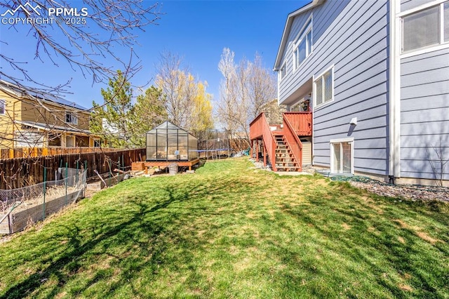 view of yard featuring a trampoline, a garden, stairway, a deck, and fence