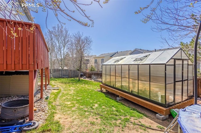view of yard with a fenced backyard, a greenhouse, and an outbuilding
