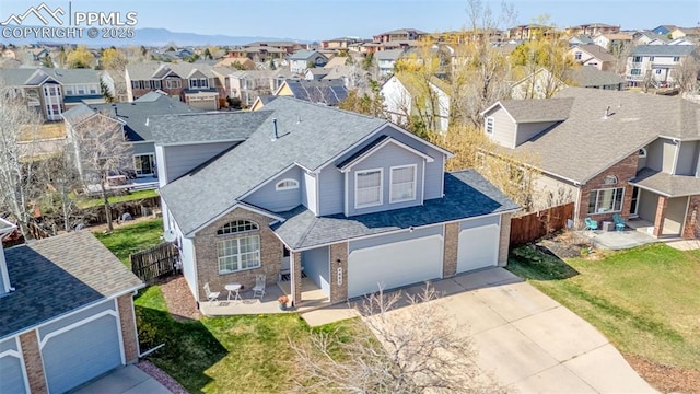 view of front of property with a shingled roof, concrete driveway, fence, and a residential view