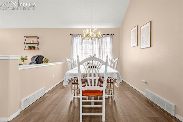 dining area featuring visible vents, vaulted ceiling, a notable chandelier, and wood finished floors