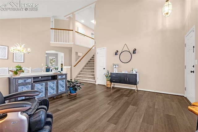 entrance foyer featuring high vaulted ceiling, an inviting chandelier, arched walkways, wood finished floors, and stairs
