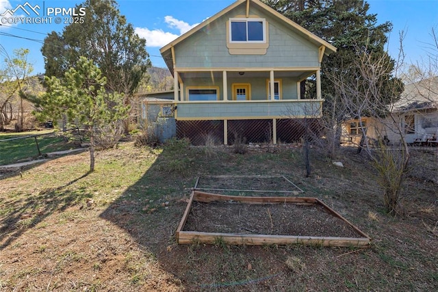 rear view of property featuring a porch, a garden, and fence