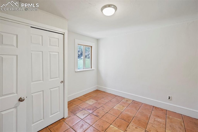 unfurnished room featuring baseboards and light tile patterned flooring