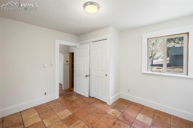 unfurnished bedroom with a closet and baseboards