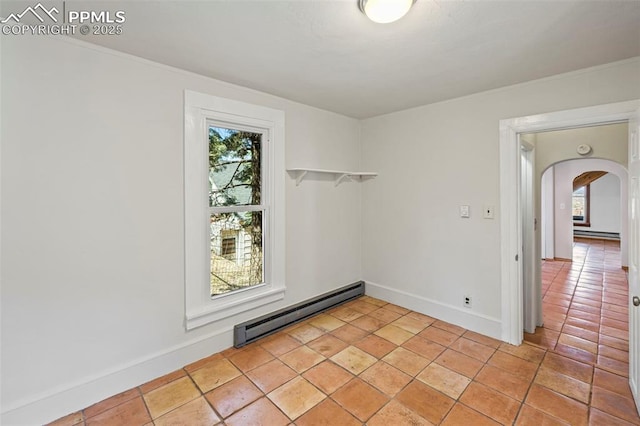 spare room featuring a wealth of natural light, arched walkways, baseboards, and baseboard heating