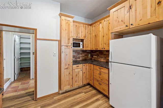 kitchen with light wood finished floors, white appliances, light brown cabinets, and decorative backsplash