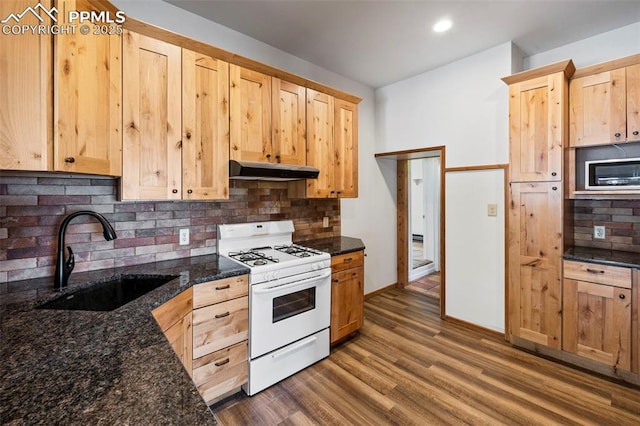 kitchen featuring light brown cabinets, white range with gas cooktop, backsplash, under cabinet range hood, and a sink