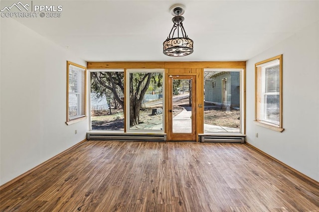 interior space featuring baseboard heating, baseboards, and wood finished floors