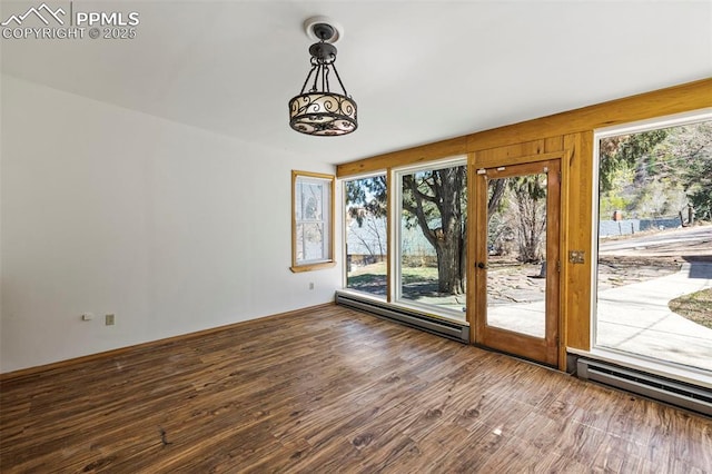 unfurnished dining area featuring plenty of natural light, a baseboard heating unit, and wood finished floors
