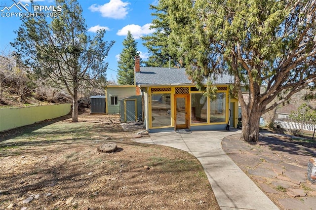 back of house with fence, a patio, and a chimney