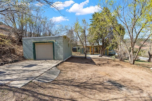 view of front facade with driveway, concrete block siding, an outdoor structure, and a garage