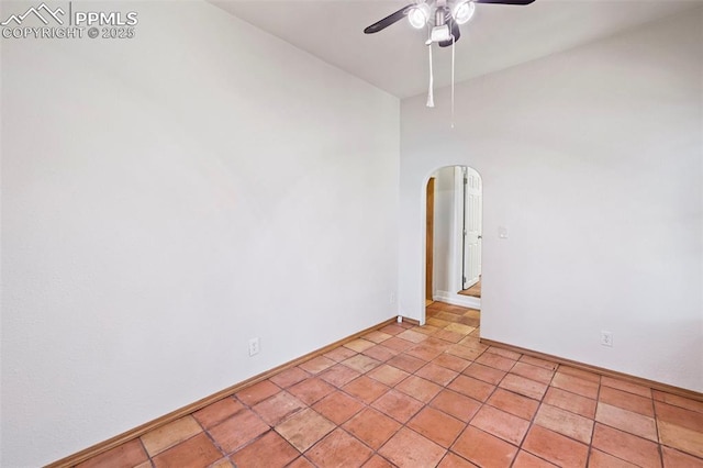 spare room featuring arched walkways, baseboards, and a ceiling fan