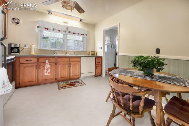 2354 Valley Forge Rd, Colorado Springs, CO 80907 - kitchen with brown cabinets, a sink, ceiling fan, a wainscoted wall, and white dishwasher