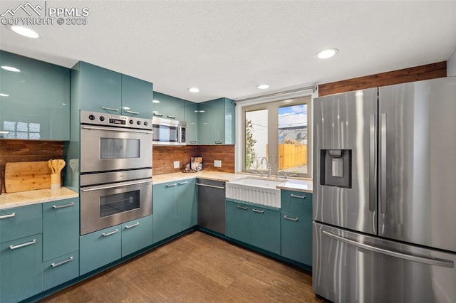kitchen with tasteful backsplash, a sink, dark wood finished floors, recessed lighting, and stainless steel appliances