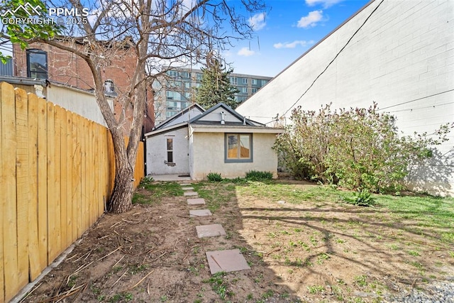 rear view of house featuring stucco siding and fence