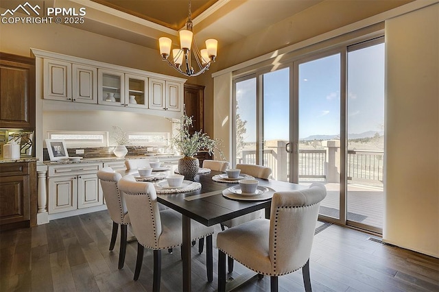 dining area featuring visible vents, a wealth of natural light, a notable chandelier, and dark wood finished floors