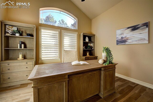 home office with baseboards, light wood-type flooring, high vaulted ceiling, and a healthy amount of sunlight