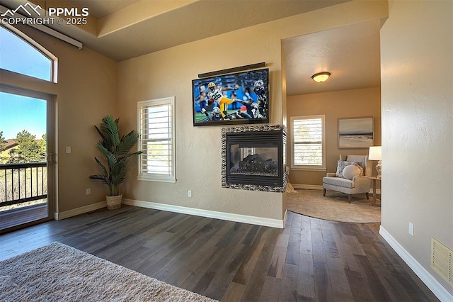 living room featuring a fireplace, dark wood-style flooring, baseboards, and visible vents