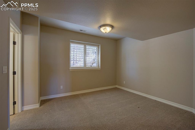 carpeted empty room featuring visible vents, baseboards, and a textured ceiling