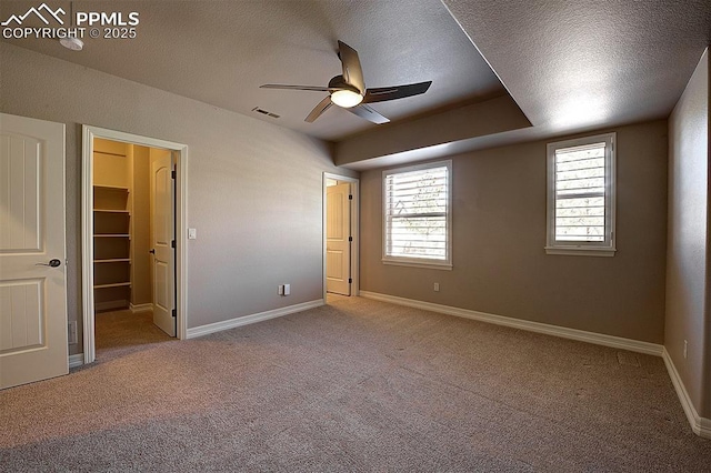unfurnished bedroom featuring a spacious closet, carpet, visible vents, and a textured ceiling