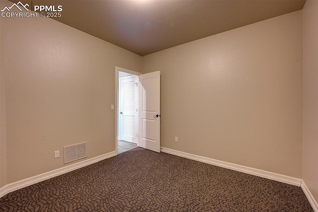 empty room featuring visible vents, baseboards, and dark colored carpet