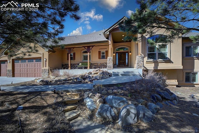 view of front facade with an attached garage, stucco siding, and stone siding