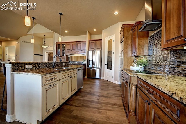 kitchen featuring dark wood-style flooring, a kitchen breakfast bar, wall chimney range hood, stainless steel appliances, and a sink