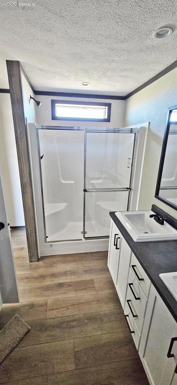 6945 N Ramah Hwy, Yoder, CO 80864 - bathroom with a sink, a shower stall, wood finished floors, and a textured ceiling