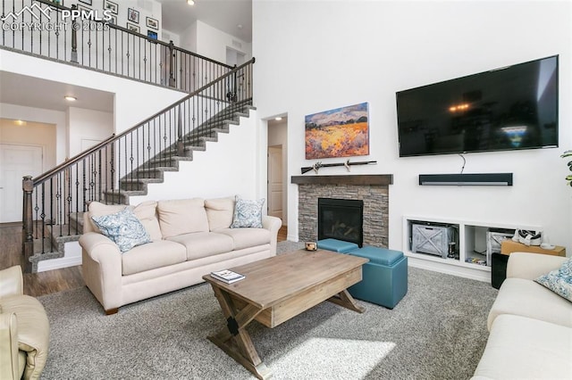 living area with a towering ceiling, stairway, a fireplace, wood finished floors, and recessed lighting