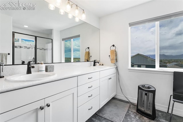 full bathroom with double vanity, baseboards, a stall shower, and a mountain view