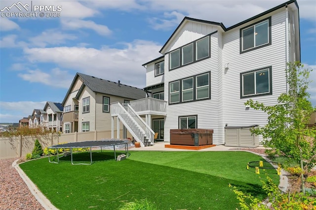 back of house with a hot tub, a trampoline, a deck, stairway, and board and batten siding