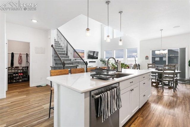 kitchen with stainless steel dishwasher, a sink, white cabinets, and light wood finished floors