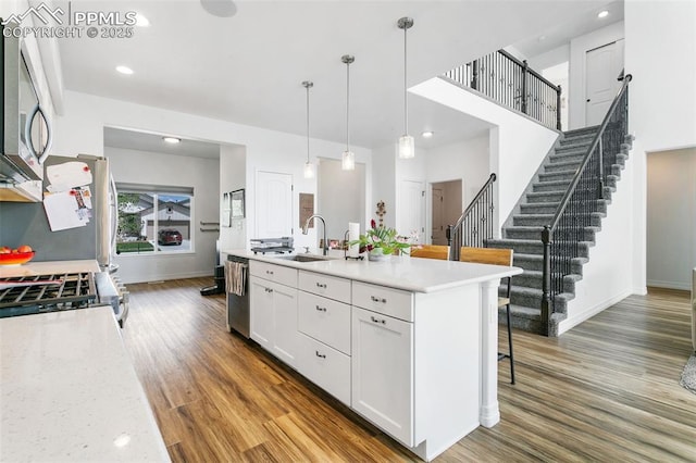 kitchen featuring a sink, white cabinetry, wood finished floors, a kitchen breakfast bar, and baseboards