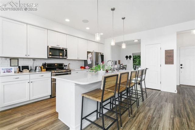 kitchen featuring stainless steel appliances, dark wood-style floors, decorative backsplash, light countertops, and white cabinets