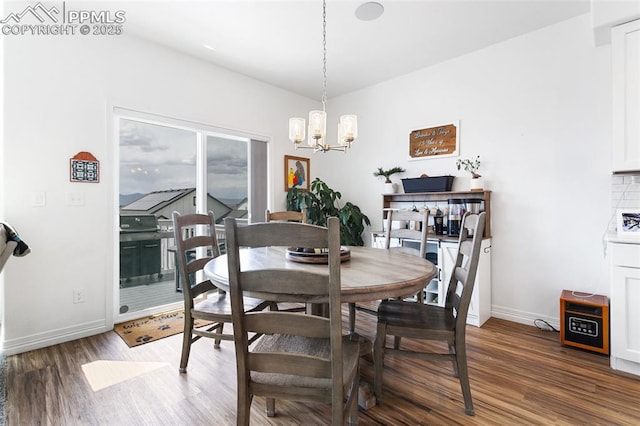 dining area featuring a chandelier, baseboards, and wood finished floors
